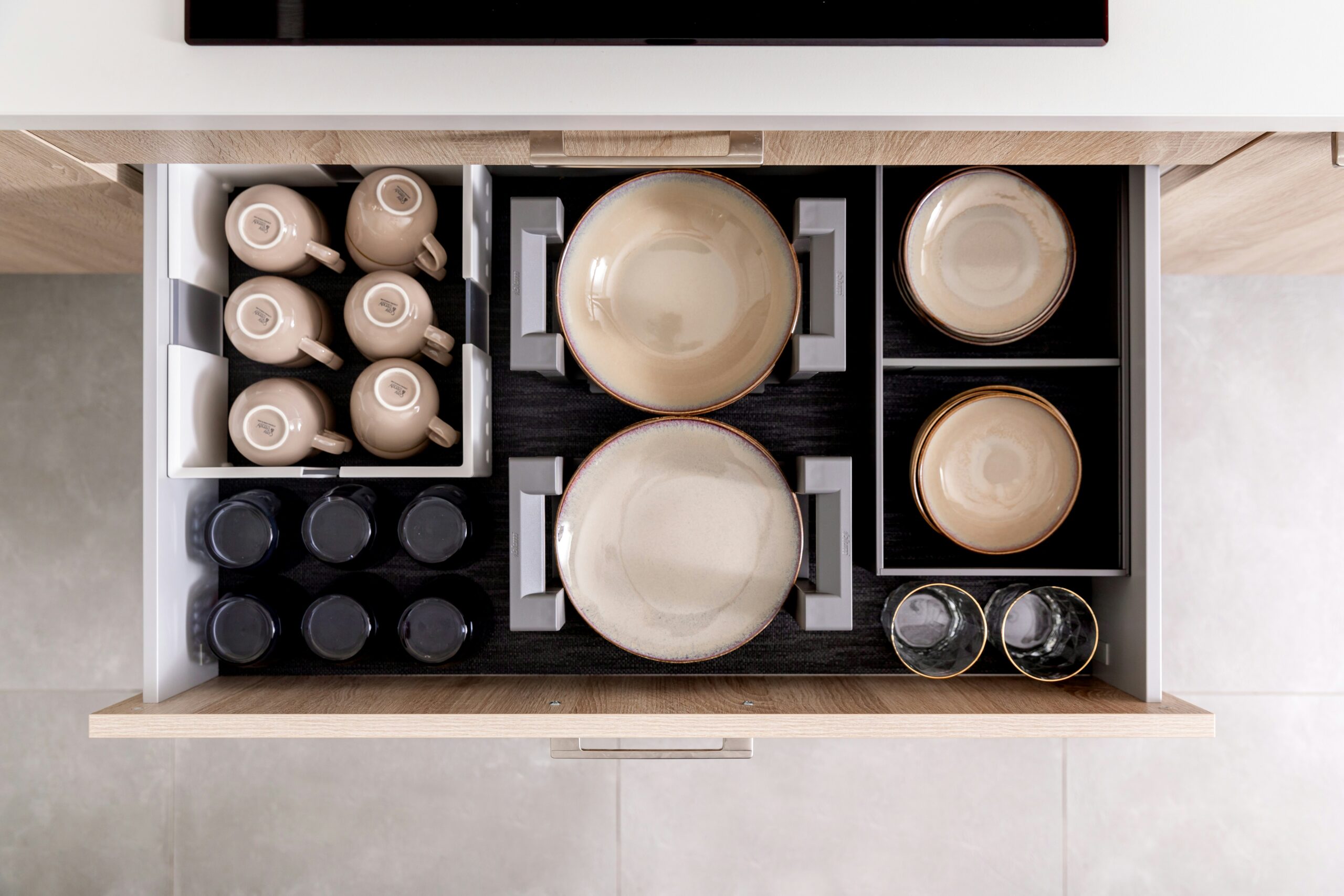 Kitchen drawer organizer holding plates, bowls, mugs, and jars neatly arranged for efficient storage.